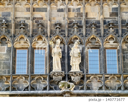 Ancient stone figures placed near intricate balustrades and reflective glass surfaces in city environments Ancient stone figures placed near intricate balustrades and reflective glass surfaces in city environments 140771677