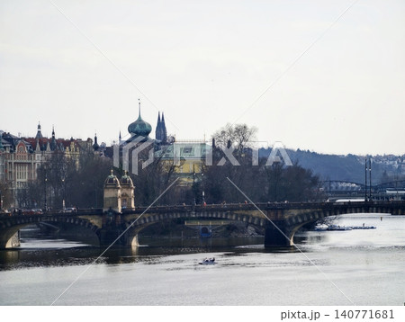 Serene river crossing at dawn. Quiet dawn with ancient bridge and distant city rooftops and spires Serene river crossing at dawn. Quiet dawn with ancient bridge and distant city rooftops and spires 140771681