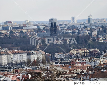 Cityscape featuring spires and layered rooftops. Moody city view with distant towers and lush hills 140771708