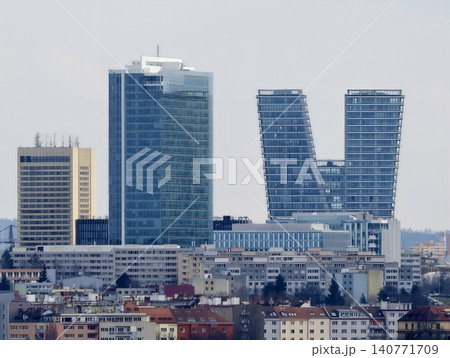 Architectural skyscrapers with reflecting surfaces ascend above lowrise rooftops in busy cityscape Architectural skyscrapers with reflecting surfaces ascend above lowrise rooftops in busy cityscape 140771709
