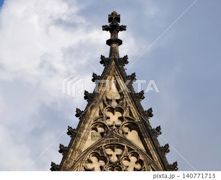 Elaborate gothic architectural ornamentation showcasing sculptural artistry against clear blue sky Elaborate gothic architectural ornamentation showcasing sculptural artistry against clear blue sky 140771713