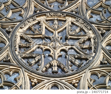 Detailed carved stone tracery forming historic rose window illuminated by contrasting sunlight 140771714