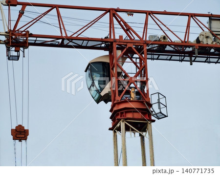 Heightened view of construction crane operator. Silhouette of heavy crane with safety gear visible Heightened view of construction crane operator. Silhouette of heavy crane with safety gear visible 140771735