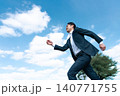 青空の下、草原を力強く歩くスーツ姿の日本人ビジネスマン 140771755