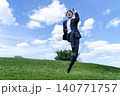 青空をバックに笑顔で大ジャンプするスーツ姿のビジネスマン 140771757