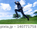 青空の下、草原を力強く歩くスーツ姿の日本人ビジネスマン 140771758