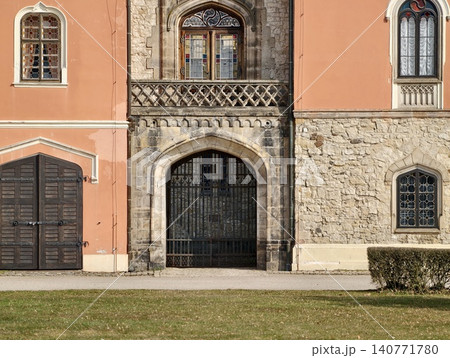 Decorative archway entry. Elegant stone arch with balcony. Ornate stone gateway featuring balcony and arch Decorative archway entry. Elegant stone arch with balcony. Ornate stone gateway featuring balcony and arch 140771780