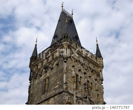 Stone monument under cloudy sky. Old stone structure showcasing battlements and historical emblems Stone monument under cloudy sky. Old stone structure showcasing battlements and historical emblems 140771797