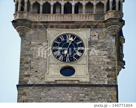 Old clock with decorative face. Landmark structure featuring weathered stone and classical clock design Old clock with decorative face. Landmark structure featuring weathered stone and classical clock design 140771804