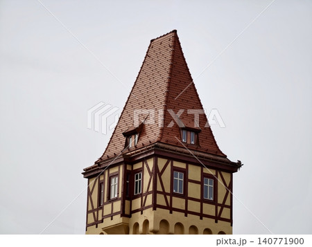 Traditional tower featuring wooden beams and tiles. Timbered tower with clay tiles in serene sky background Traditional tower featuring wooden beams and tiles. Timbered tower with clay tiles in serene sky background 140771900