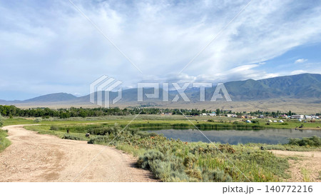 View of a rural dirt road near the Issyk-Kul mountain lake in Kyrgyzstan, Asia. Travel and tourism. Trekking and hiking. Mountain landscape. Beautiful summer panorama of a small village 140772216