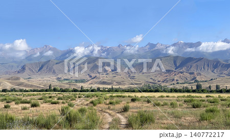 A breathtaking landscape overlooking the amazing mountains, hills and cliffs of Kyrgyzstan near Lake Issyk Kul. View of a rural dirt road. Travel and tourism. Trekking and hiking 140772217