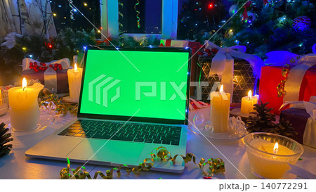 Beautifully packaged gift boxes, burning candles, pine cones, confetti, fir branch with red berries and striped caramel. Christmas advertising concept on computer. Laptop with a chroma key Beautifully packaged gift boxes, burning candles, pine cones, confetti, fir branch with red berries and striped caramel. Christmas advertising concept on computer. Laptop with a chroma key 140772291