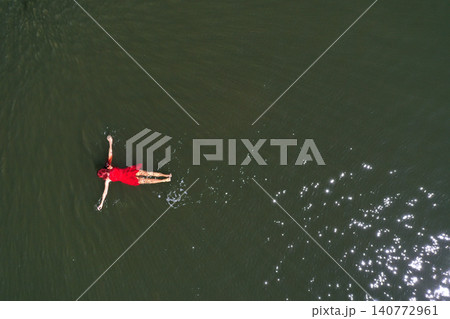 Woman in a red dress floating in water aerial view Woman in a red dress floating in water aerial view 140772961