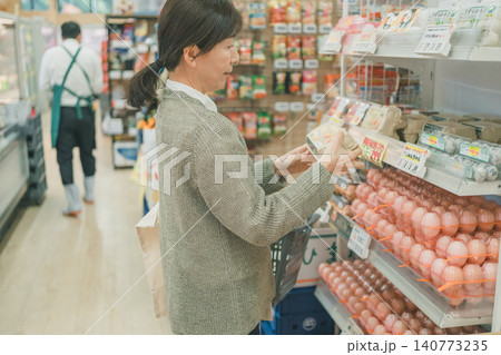 スーパーでたまごを手に取り確認する中高年女性客 スーパーでたまごを手に取り確認する中高年女性客 140773235