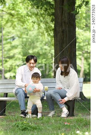 公園のベンチに座ってくつろぐ若い夫婦と愛娘 公園のベンチに座ってくつろぐ若い夫婦と愛娘 140773928