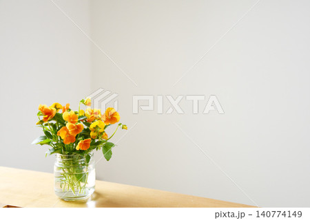 白い壁と木のテーブルに置かれたオレンジ色の花の花瓶 余白のあるシンプル写真 白い壁と木のテーブルに置かれたオレンジ色の花の花瓶 余白のあるシンプル写真 140774149