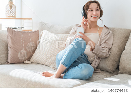 家でソファーに座ってヘッドホンで音楽を聴くリラックスした女性 家でソファーに座ってヘッドホンで音楽を聴くリラックスした女性 140774458