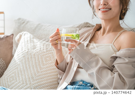 ソファーに座りレモン水,デトックスウォーターを飲む女性 ソファーに座りレモン水,デトックスウォーターを飲む女性 140774642