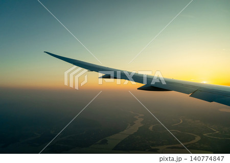 Airplane wing above Osaka coast during sunset descent flight 140774847