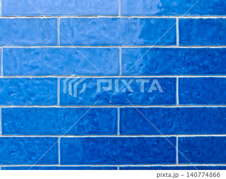A close-up of a wall featuring various shades of blue rectangular tiles A close-up of a wall featuring various shades of blue rectangular tiles 140774866