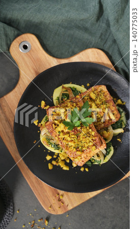 Baked tofu steak with herb breadcrumb crust over sauteed greens Baked tofu steak with herb breadcrumb crust over sauteed greens 140775033