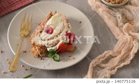 A slice of sweet meringue roll cake with cream and fresh berries on a plate A slice of sweet meringue roll cake with cream and fresh berries on a plate 140775116