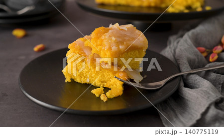 A slice of moist orange cake with citrus glaze on a black plate A slice of moist orange cake with citrus glaze on a black plate 140775119