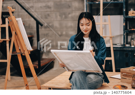Female artist wears black hat posing near picture indoor the studio Female artist wears black hat posing near picture indoor the studio 140775604