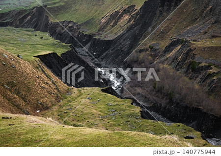 a deep canyon with a narrow river flowing along its rocky bottom a deep canyon with a narrow river flowing along its rocky bottom 140775944