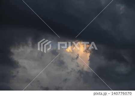 Dramatic storm clouds with a glowing golden light breaking through the dark sky at sunset, contrast of light and shadow. Dramatic storm clouds with a glowing golden light breaking through the dark sky at sunset, contrast of light and shadow. 140776070