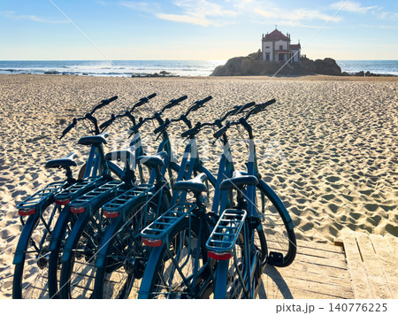 Bicycles Parked on the Sand with Capela do Senhor da Pedra in the Distance at Praia de Miramar Bicycles Parked on the Sand with Capela do Senhor da Pedra in the Distance at Praia de Miramar 140776225