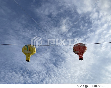 Two Hot Air Balloon Shaped Lanterns Hanging On Wire Against Sky Two Hot Air Balloon Shaped Lanterns Hanging On Wire Against Sky 140776366