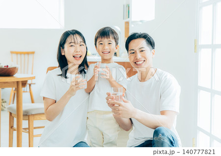 リビングで水を飲む若い家族 140777821