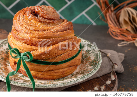 Beautifully baked puff pastry Easter cruffin coated in cinnamon sugar and tied with a green velvet bow on a vintage plate with rustic spring decor Beautifully baked puff pastry Easter cruffin coated in cinnamon sugar and tied with a green velvet bow on a vintage plate with rustic spring decor 140779759