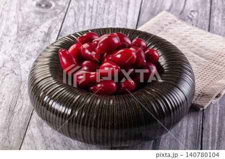 Red berries in textured dark bowl on rustic wooden surface Red berries in textured dark bowl on rustic wooden surface 140780104