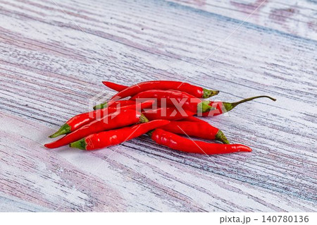 Red chili peppers on weathered wooden surface 140780136