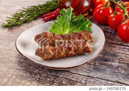 Grilled meat skewers on ceramic plate with fresh vegetables and herbs Grilled meat skewers on ceramic plate with fresh vegetables and herbs 140780170