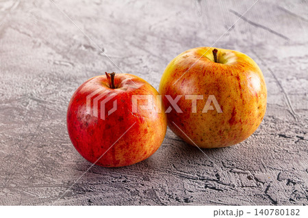 Two ripe apples on textured gray surface 140780182