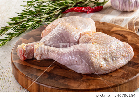 Raw chicken legs on wooden cutting board with rosemary garlic and chili peppers 140780184