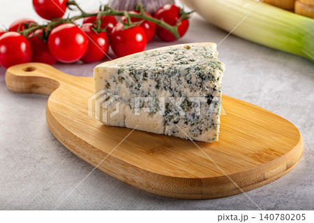 Blue cheese wedge on wooden board with cherry tomatoes and leek background Blue cheese wedge on wooden board with cherry tomatoes and leek background 140780205