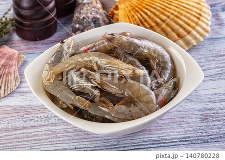 Fresh raw shrimp in white bowl with seashells and wooden table background Fresh raw shrimp in white bowl with seashells and wooden table background 140780228