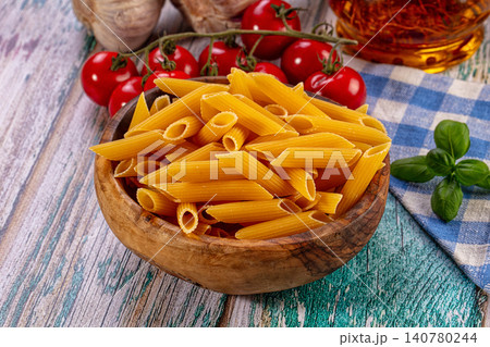 Penne pasta in wooden bowl with cherry tomatoes and basil on rustic table Penne pasta in wooden bowl with cherry tomatoes and basil on rustic table 140780244