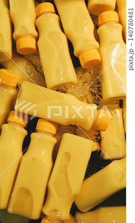 Top view of yellow juice plastic bottles chilled on crushed ice, fresh sweet corn milk beverage display for sale. Top view of yellow juice plastic bottles chilled on crushed ice, fresh sweet corn milk beverage display for sale. 140780481