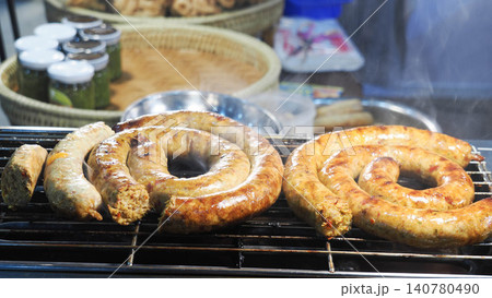 Selective focus of hot grilled Thai spicy sausages, traditional local food menu background with chili paste jars. 140780490