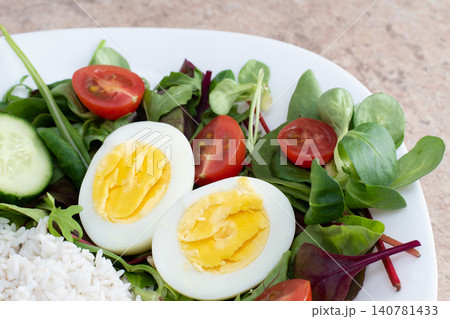 Salad of green vegetables, tomato and rice in a white plate. Rice with vegetables and eggs on a white plate. Salad of green vegetables, tomato and rice in a white plate. Rice with vegetables and eggs on a white plate. 140781433