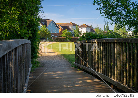 A modern housing development in Mersham, Surrey, UK. A path over a small wooden bridge leads to the houses. A modern housing development in Mersham, Surrey, UK. A path over a small wooden bridge leads to the houses. 140782395