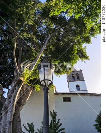 Historic church tower behind leafy tree and lamp post Historic church tower behind leafy tree and lamp post 140782586