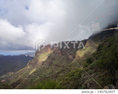 Mountain road through dramatic cloudy canyon landscape Mountain road through dramatic cloudy canyon landscape 140782607