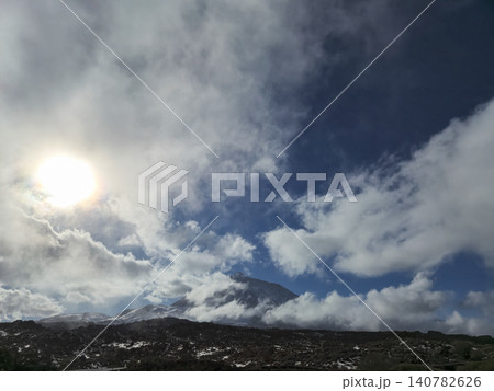 Sunlit volcanic mountain under dramatic cloudy sky Sunlit volcanic mountain under dramatic cloudy sky 140782626